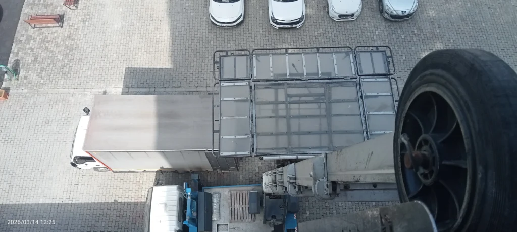 Trabzon Yomra asansörlü evden eve nakliyat nakliye asansöründen inen eşyaların direk arabaya yüklenmesini gösteren görsel bir nakliye kamyonu bir asansörlü vinç.